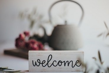 IWCE Area Representatives - Welcome sign and a white teapot -  Photo by Carolyn V on Unsplash